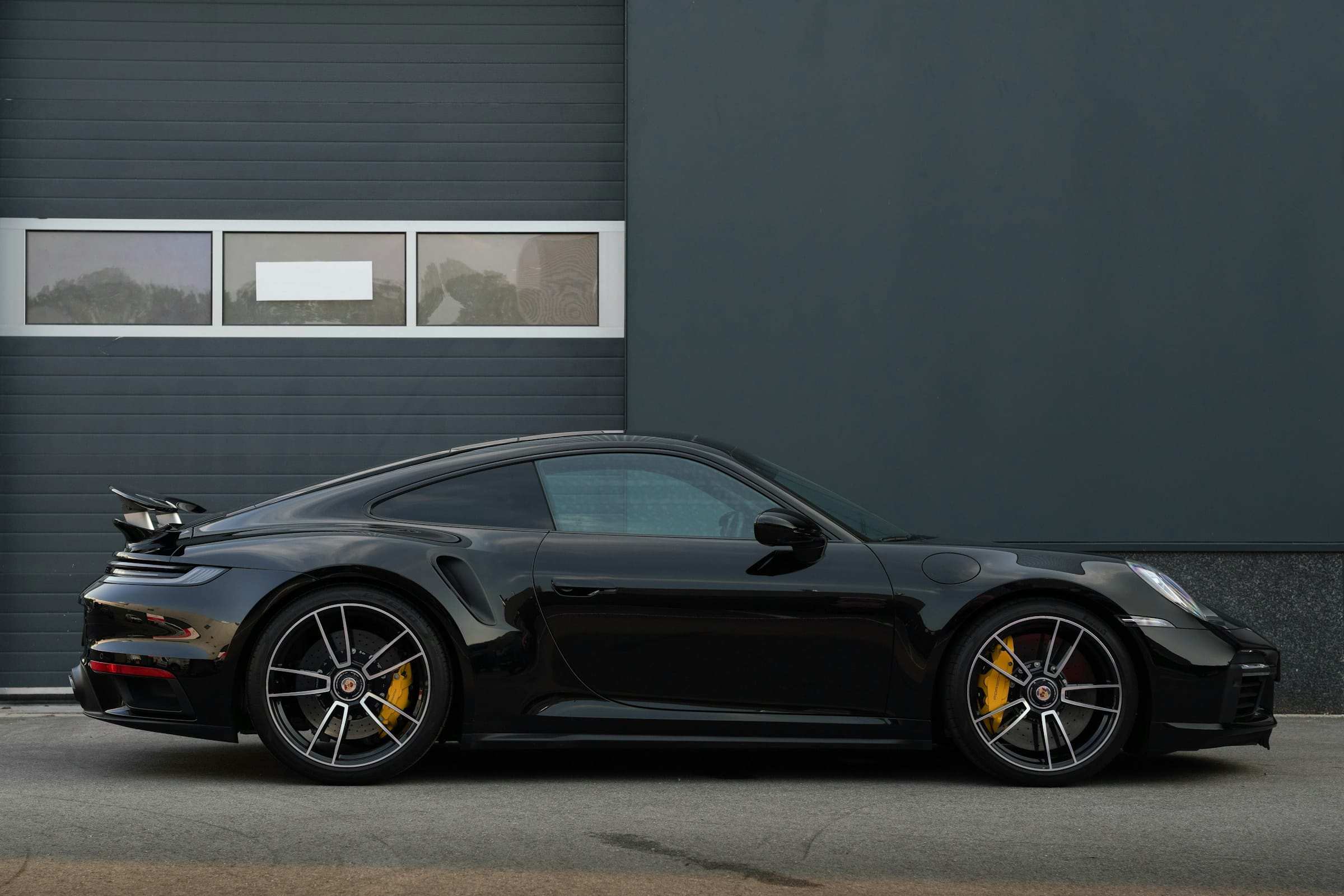 Black Porsche 911 Turbo S in side profile against a dark wall